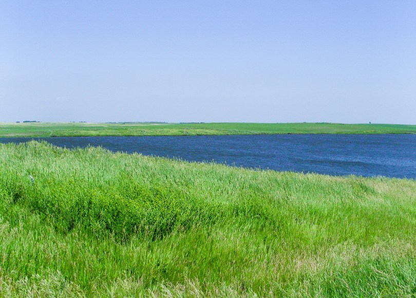 Rolling green prairie grasses next to beautiful blue lake
